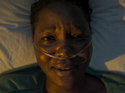 Black woman laying on a hospital bed in pain